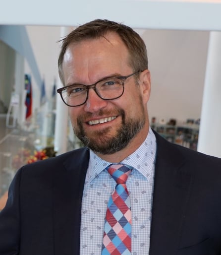 Portrait of a man wearing a suit and glasses with a patterned shirt and tie